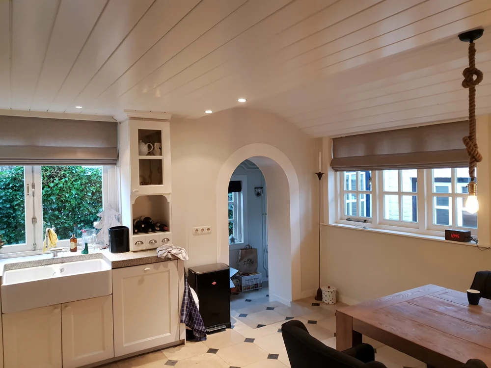 Taupekleurige vouwgordijnen in een lichte keuken