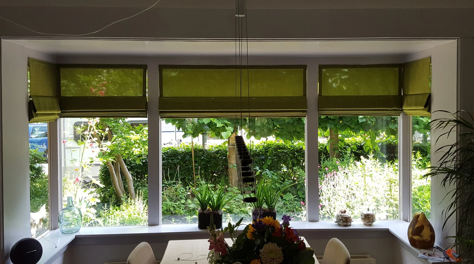 Groene vouwgordijnen in een eetkamer met uitzicht op de tuin