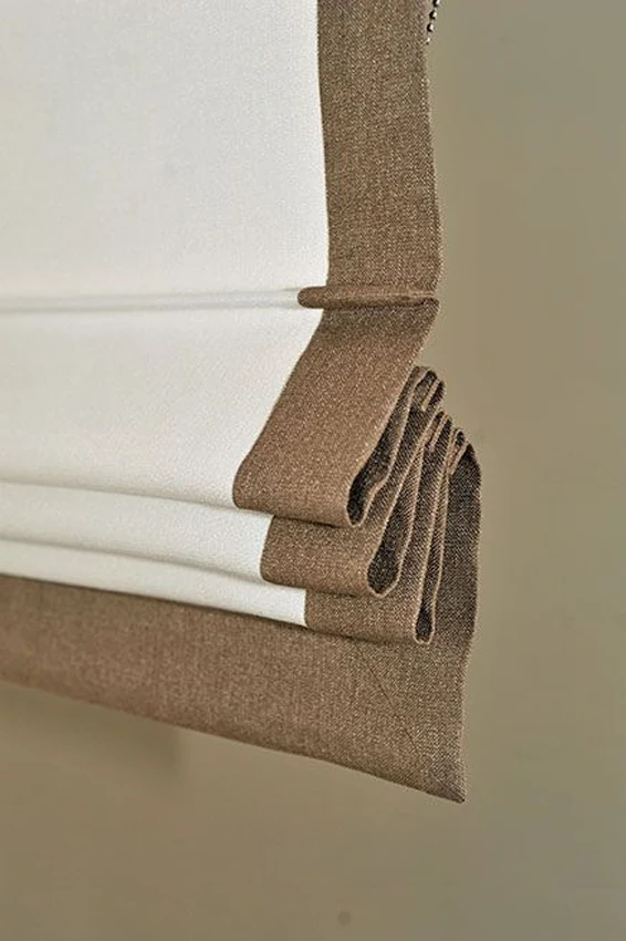 Detail van een taupekleurig vouwgordijn met nette onderafwerking