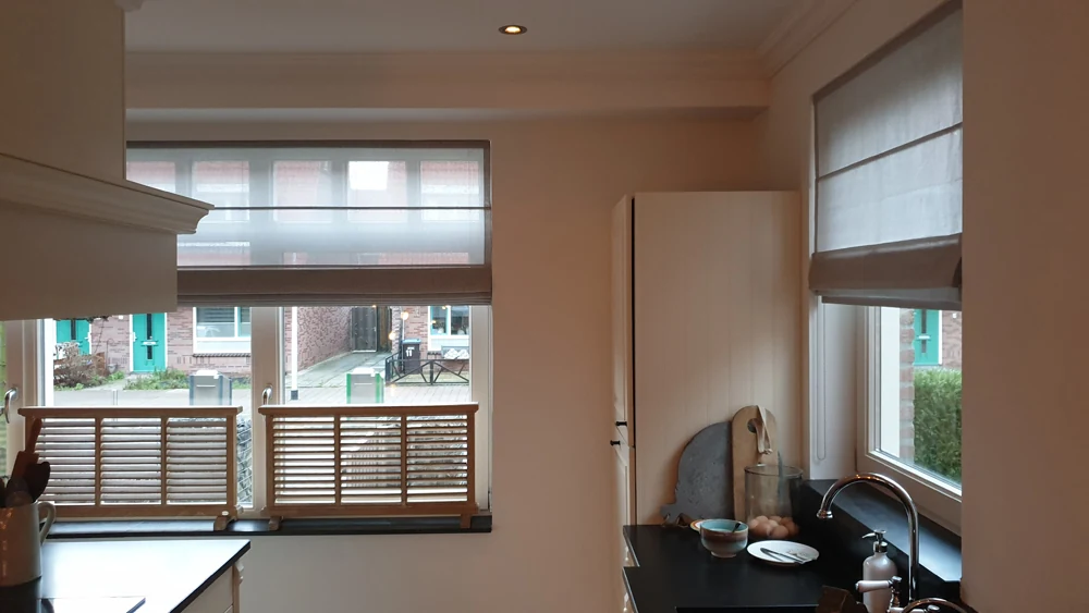 Lichte vouwgordijnen bij twee ramen in een woonkamer