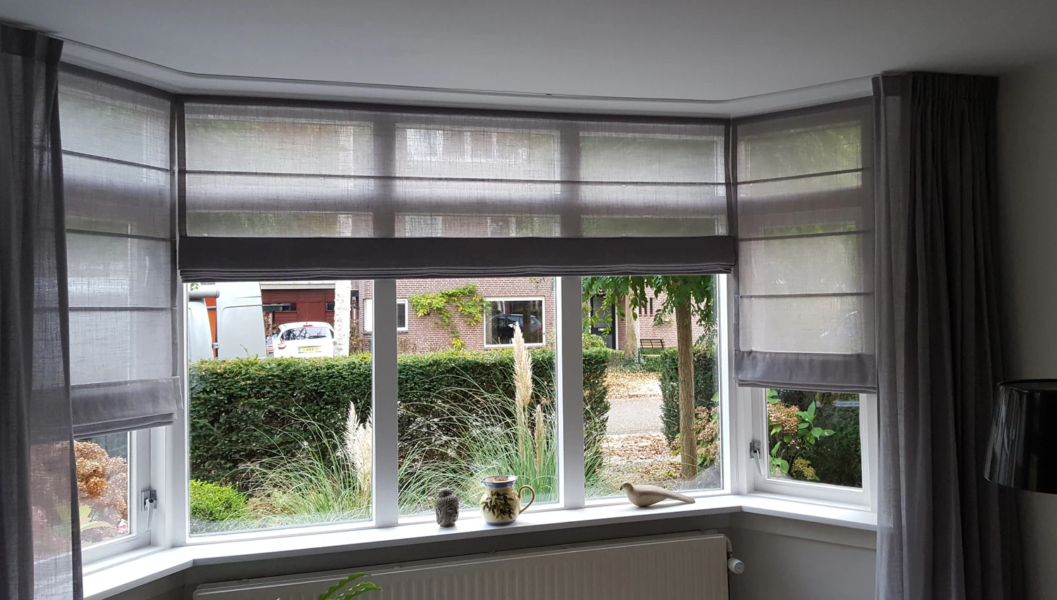 Lichtdoorlatende vouwgordijnen in een erker met overgordijnen